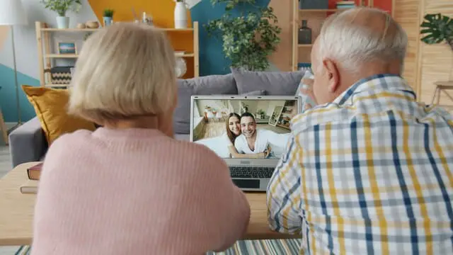 Seniorenpaar sitzt vor einem Laptop bei einem Videoanruf